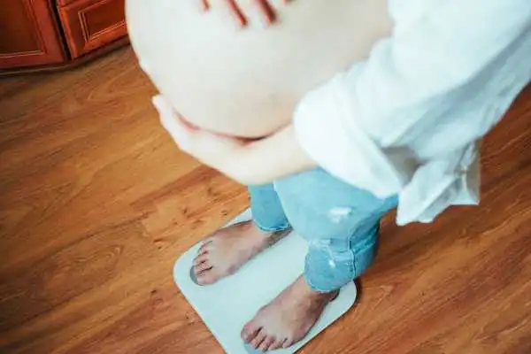 Image of woman weighing herself and experiencing weight gain through pregnancy Blackburn
